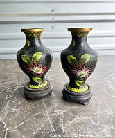 Front view of both vases on stands showing primary floral design and brass rims