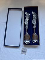 Closed presentation box alongside spoon and fork in open display showing ornate leaf handles