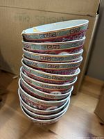 Stack of 12 red porcelain bowls showing pattern and chips