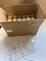 Cardboard box open showing rows of jars and label sheet