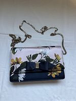 Front view showing floral print, bow detail, chain strap