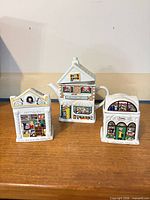 Front view of all three ceramic house-shaped pieces on table