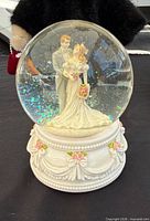 Front view of snow globe showing bride and groom figures and base detail