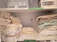 Shelved stacks of assorted white, cream and patterned towels
