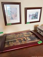 Overview showing two small framed prints on wall and larger tray-framed print lying flat