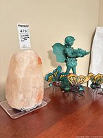 Salt lamp, fairy statue and two butterfly sculptures on tabletop