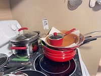 Stack of Red Copper pans and pots with copper interiors and small saucepan with lid visible