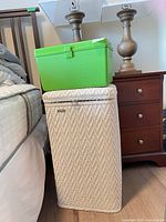 Hamper beside bed with green sewing box on lid