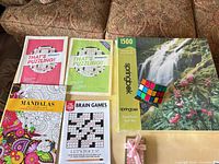 All items arranged on surface: puzzle box, cube on stand, four books, gift tin