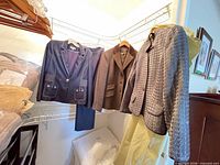Three blazers hanging; navy, brown, gray; trousers partly visible