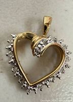 Front view of heart pendant showing yellow gold frame and clear stone border