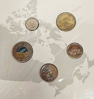 Front view of five coins mounted in sealed pack showing reverses and Canada map background