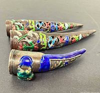 Side view of three enamel fingernail guards showing taper and openwork design