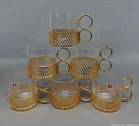All five Iittala Tsaikka glasses stacked showing gold lattice holders and ring handles