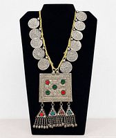 Full view of necklace on stand showing coins, pendant and fringe