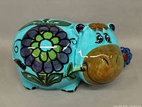 Front left view of ceramic hippopotamus coin bank showing floral motif and facial details