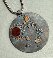 Front view of pendant showing enamel design and chain bail