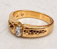 Angled view showing gold band, oval clear stone, honeycomb shoulders, 18K GD mark