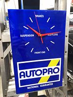 Front view of blue Autopro wall clock showing logo, red hands, white markings