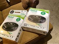 Two iRobot Roomba 595 Pet Series boxes on sofa