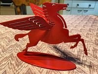 Left profile view of red metal Pegasus figurine on stand