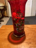 Full view of red glass vase showing height, floral and butterfly painting, gold trim