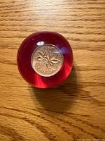 Top view showing 1974 Canada 1-cent coin embedded in clear acrylic with red background