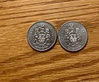 Obverse sides of two Canadian 50-cent coins dated 1976 and 1979 showing coat of arms