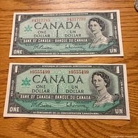 Front of two 1967 Canada one-dollar banknotes showing serial numbers and Queen Elizabeth II portrait