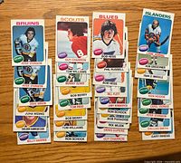Front view showing four stacks of 1975-76 OPC cards highlighting players from Bruins, Scouts, Blues, Islanders
