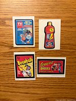 Front view of four Wacky Packages stickers arranged on wooden surface