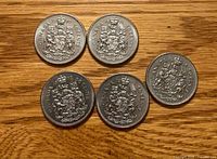 Reverse side of five Canadian 50-cent coins showing coat of arms