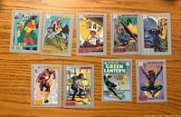 Fronts of nine DC Cosmic Cards on wooden surface
