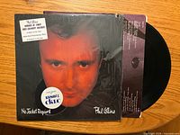 Front cover of Phil Collins No Jacket Required LP in shrink with hype stickers, record partially visible