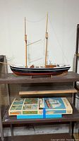 Full view of unfinished model ship on stand, box beneath
