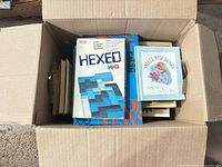 Box with Hexed Hi-Q game on top, various books visible