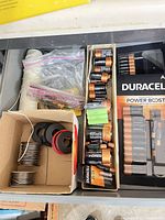 Drawer view with loose Duracell AA, C batteries, green rechargeables, wire spools and packaging