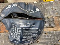 Blue round zip bag partially open showing cables and four black terminal caps