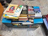 Top view of open produce box filled with stacked paperbacks and a comic book on top