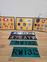 Overall lot showing three framed crest displays and four license plates