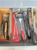 Overview of all tools in drawer including packaged pliers, trim tool, mallet, surform, files