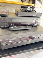 Front view of Sharp VCR, Toshiba changer, Sony DVD player with remotes