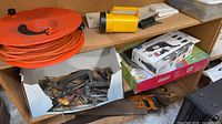 Shelf with Dremel Multi-Max box, extension cord reel, flashlight, clamps, saws