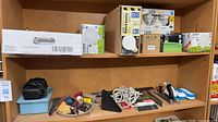 Overview of shelf with boxed LED bulbs, loose tools, rope, chargers