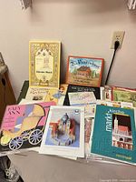 Overview showing multiple paper model kits, paper doll books and illustrated books spread on table