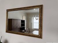 Full view of rectangular gilt wall mirror mounted on wall