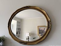 Full view of oval gilt wall mirror on wall