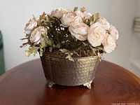 Full view of hammered brass footed planter with faux floral arrangement