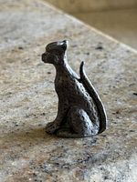 Left profile of pewter cheetah figurine on stone surface