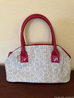 Front view of Calvin Klein monogram purse showing red patent leather handles and trim
